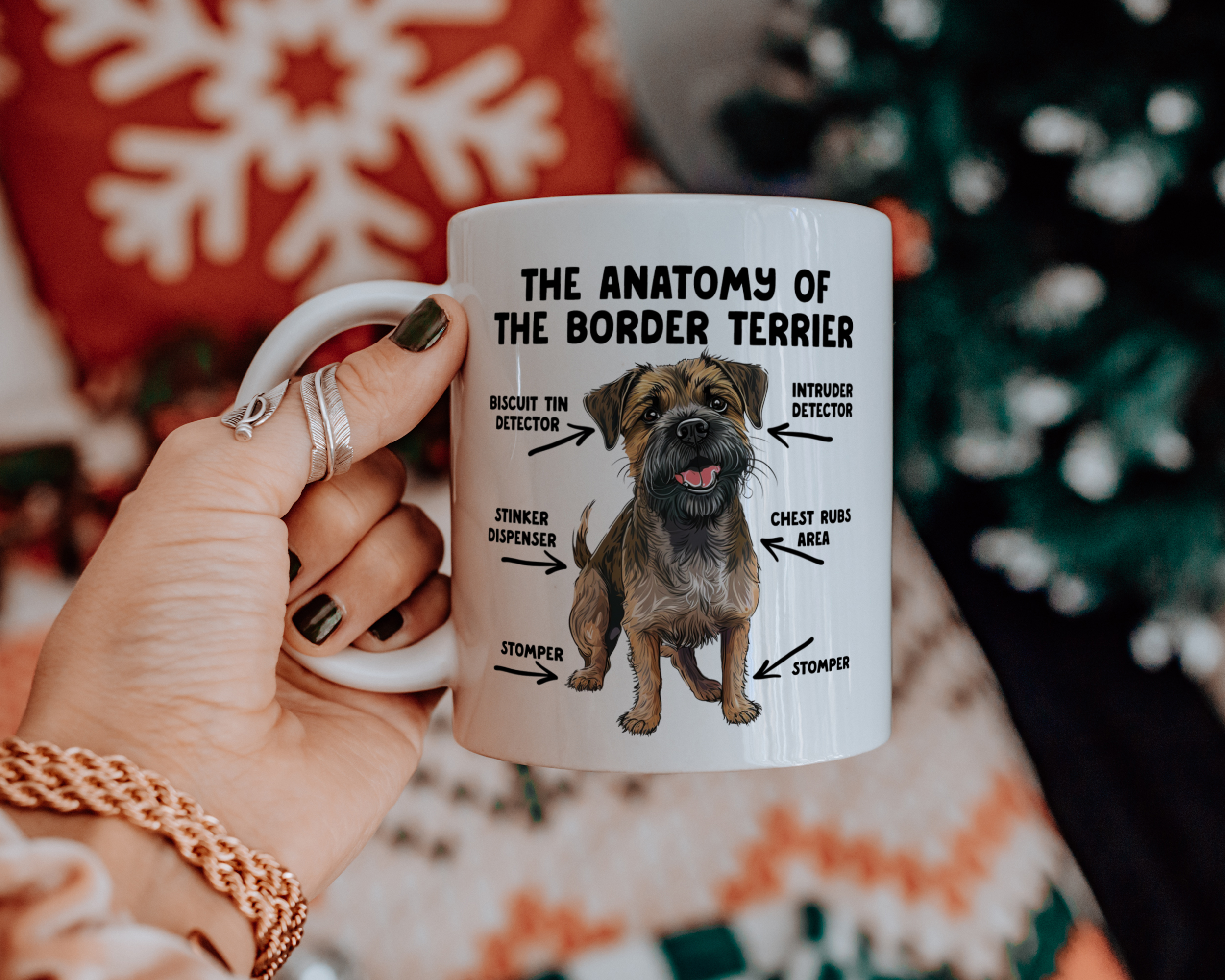 a hand holding a white ceramic mug that feature an illustration of a Border Terrier with text surrounding it reading 'the anatomy of the border terrier'.