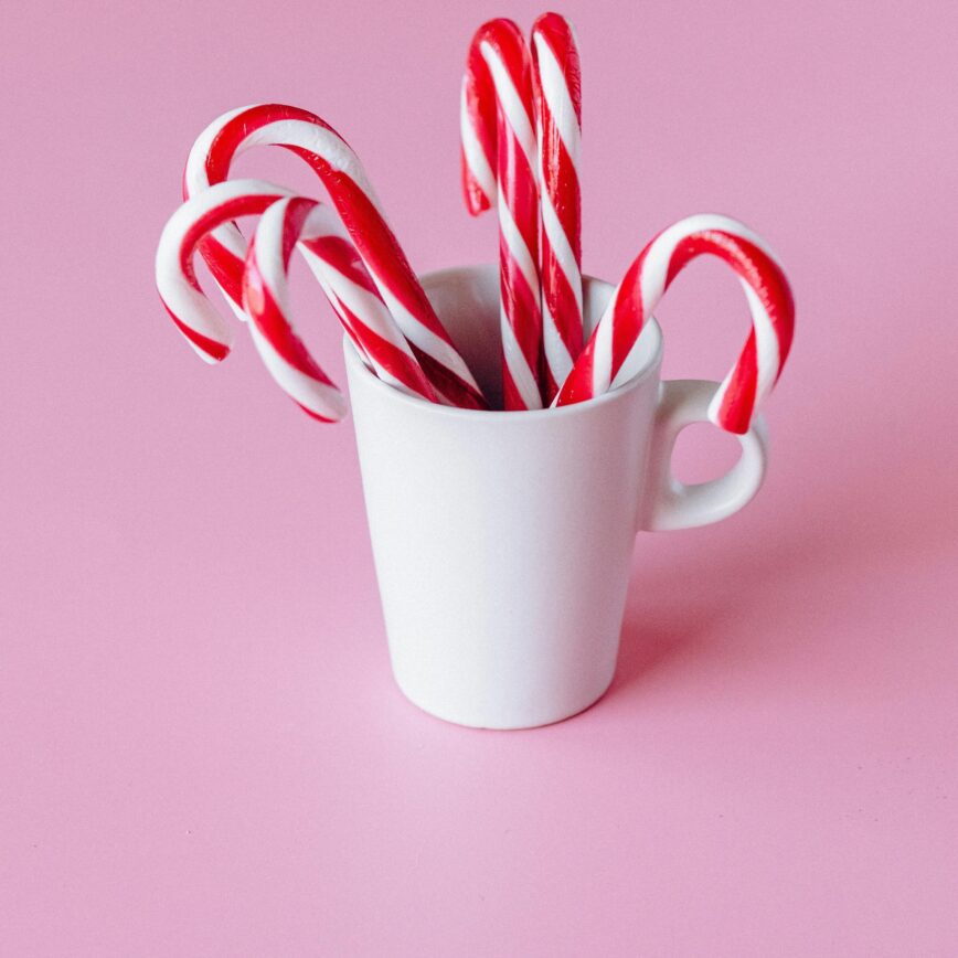 mug filled with candycanes on a pink background