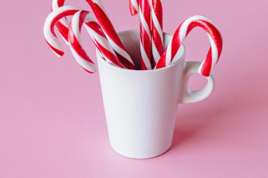 mug filled with candycanes on a pink background