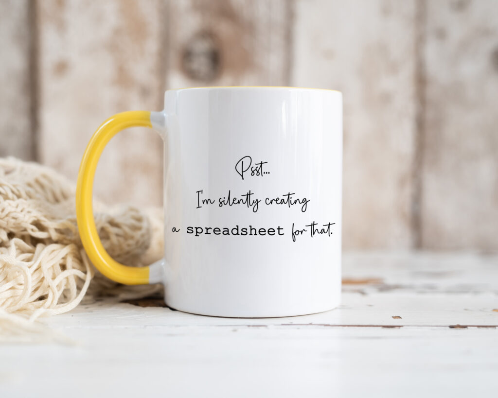 a white ceramic mug showing the text 'psst... i'm silently creating a spreadsheet for that.'